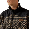 Person wearing a black and beige patterned jacket with Ariat logo.