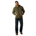 Man wearing an olive green hoodie and dark jeans on a white background