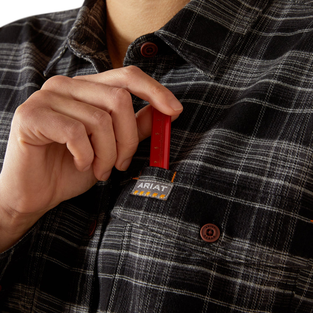 Person wearing a plaid shirt with a red tool in pocket and Ariat logo. Workwear shirt basic work station shirt uniform