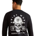 Person wearing a black long-sleeve shirt with a skull and hard hat graphic on the back, featuring 'Ariat Work' branding.