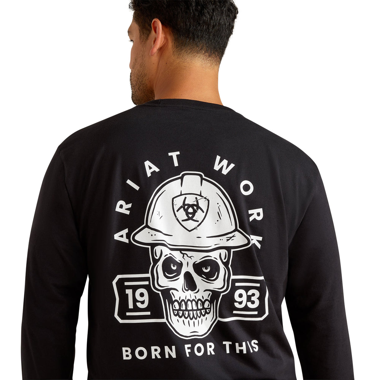 Person wearing a black long-sleeve shirt with a skull and hard hat graphic on the back, featuring 'Ariat Work' branding.