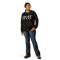 Person wearing a black Ariat sweatshirt and blue jeans on a white background