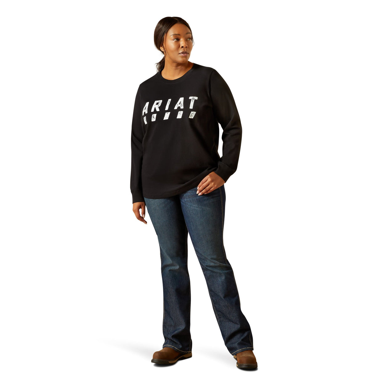 Person wearing a black Ariat sweatshirt and blue jeans on a white background