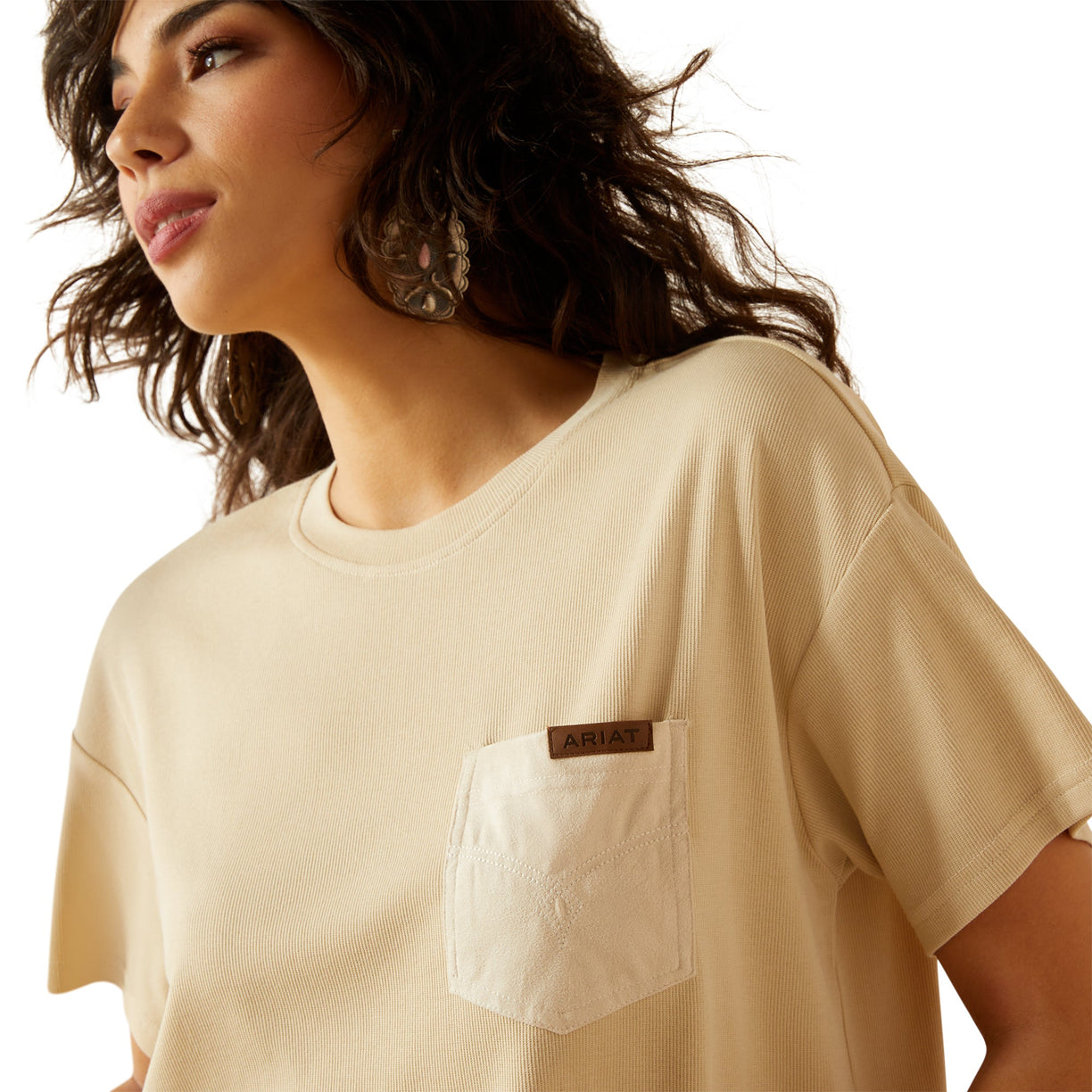 Woman wearing a beige t-shirt with a brand logo on a white background