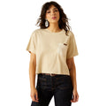 Woman wearing a beige t-shirt with a pocket and dark jeans on a white background
