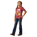 Young girl wearing a red t-shirt with a floral design and blue jeans on a white background