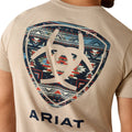 Beige t-shirt with geometric pattern and 'Ariat' branding on a person wearing it.