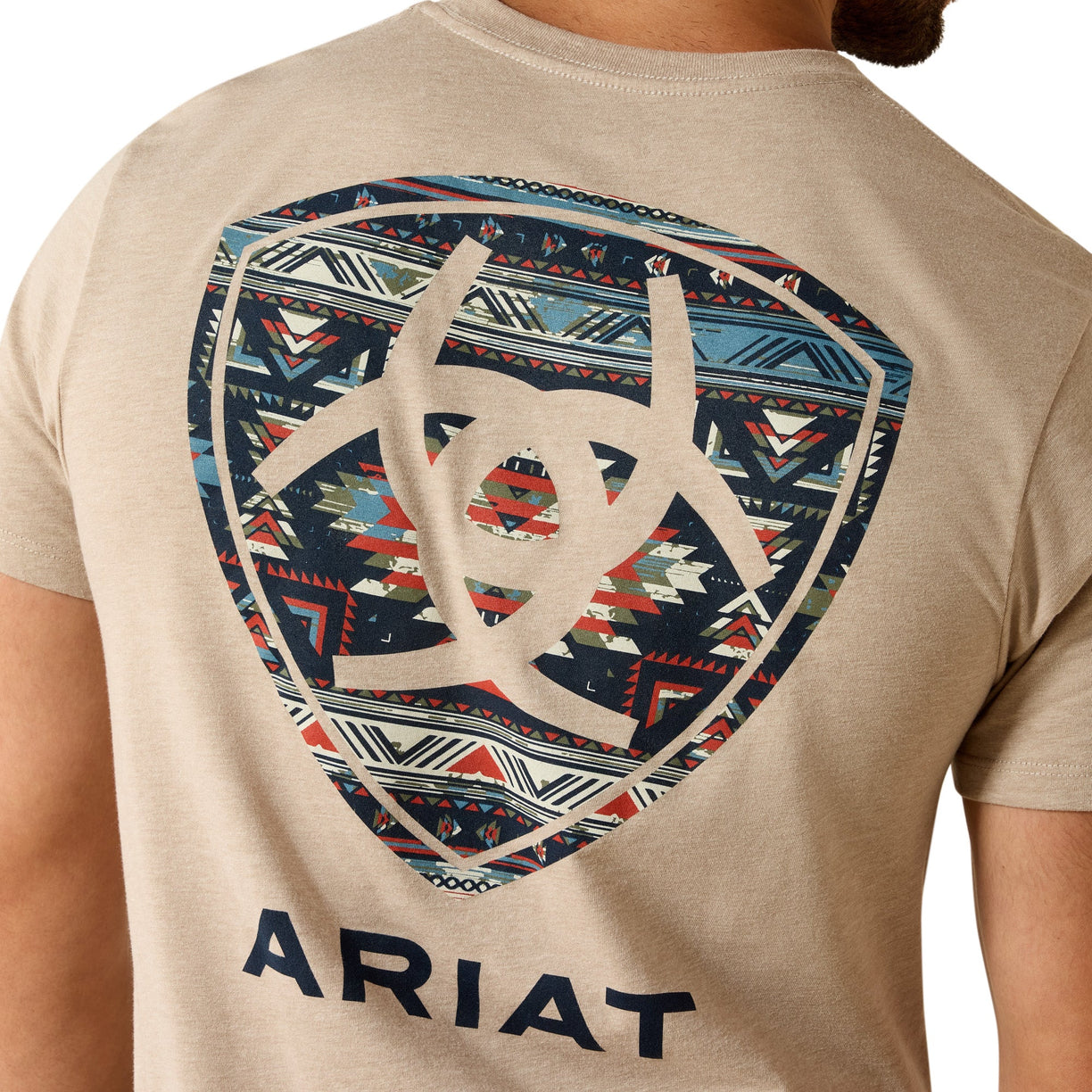 Beige t-shirt with geometric pattern and 'Ariat' branding on a person wearing it.