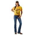 Woman wearing a yellow Ariat t-shirt and blue jeans on a white background