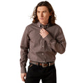 Man wearing a patterned shirt and black pants against a beige background