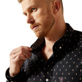 Man adjusting his collar wearing a black patterned shirt on a white background
