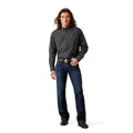 Man wearing a black patterned shirt and blue jeans on a white background