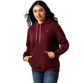 Woman wearing a maroon hoodie with pink drawstrings on a beige background