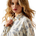 Woman wearing a cream-colored shirt with black pattern on a white background