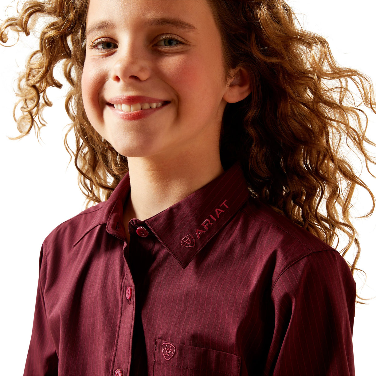 Child wearing a maroon Ariat shirt with a plain background