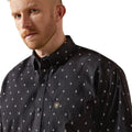 Man wearing a black patterned shirt against a white background