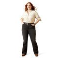 Woman wearing a beige shirt and dark jeans on a white background