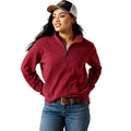 Woman wearing a red pullover, blue jeans, and a cap on a white background