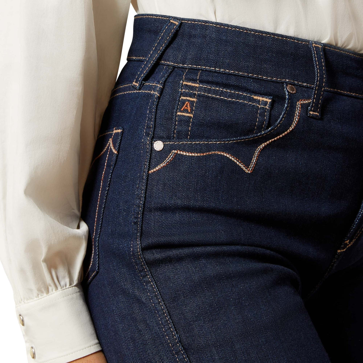 Close-up of dark blue jeans with a brand logo on a white background
