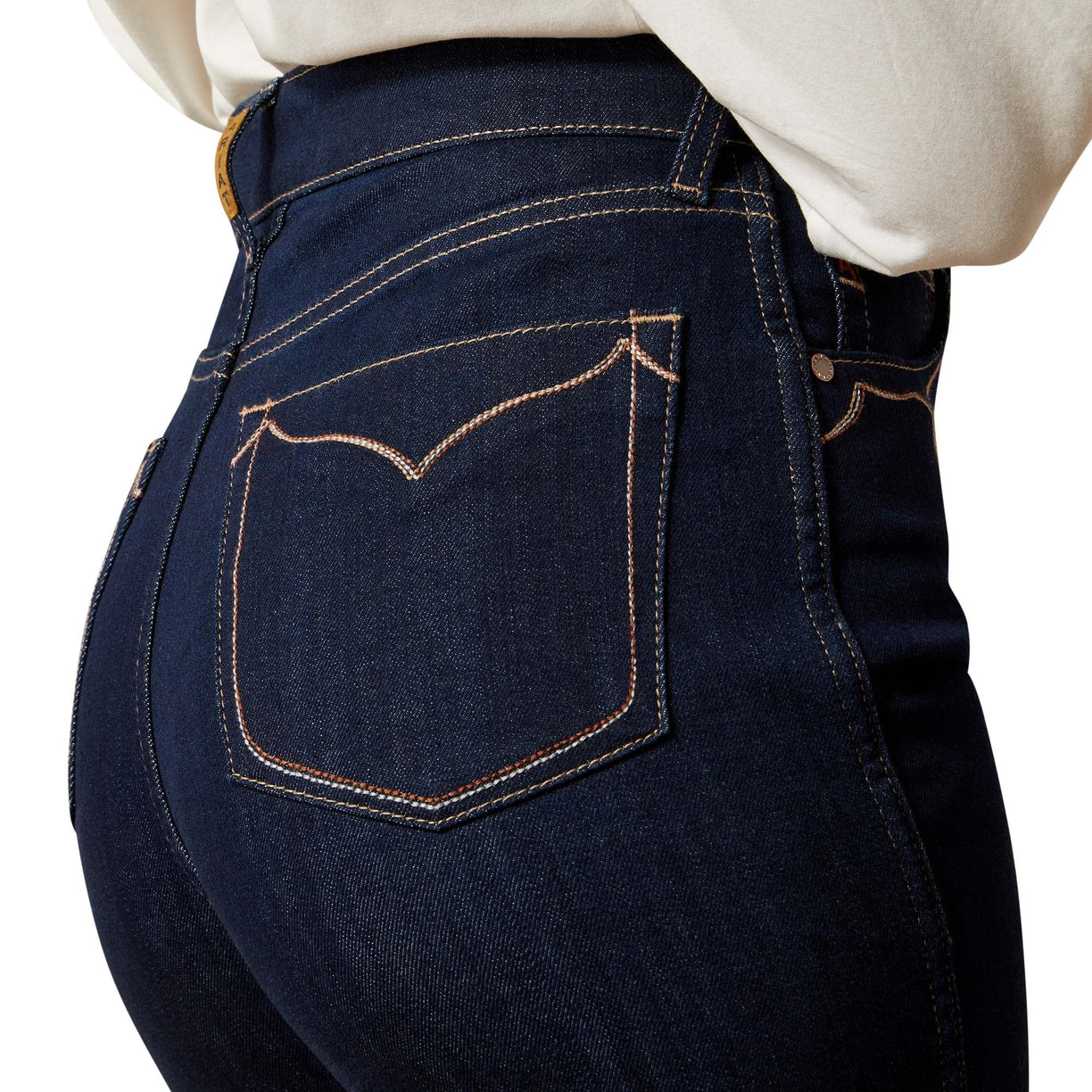 Close-up of dark blue jeans with a white shirt underneath on a white background