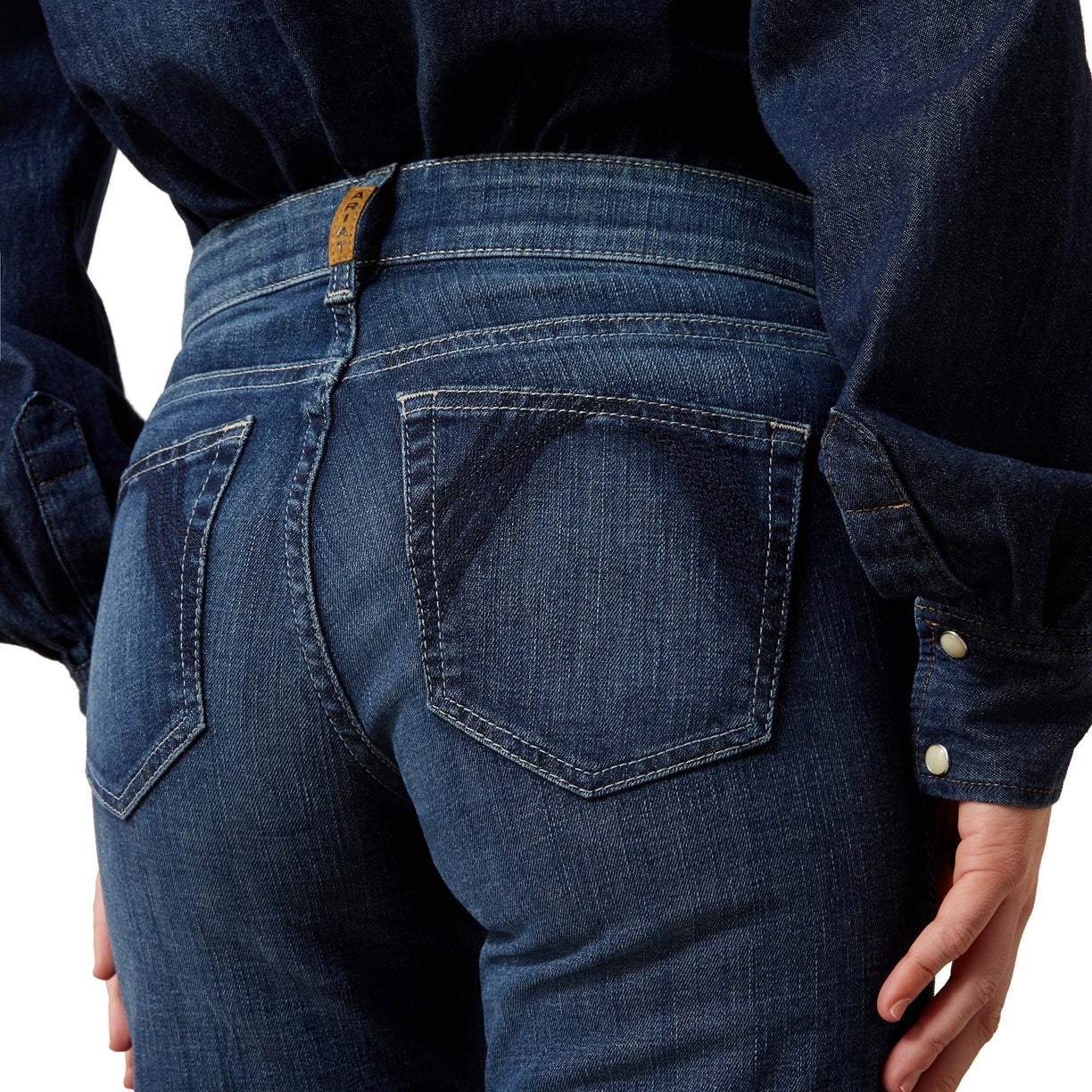 Person wearing blue jeans with a focus on the back pocket and waistband.