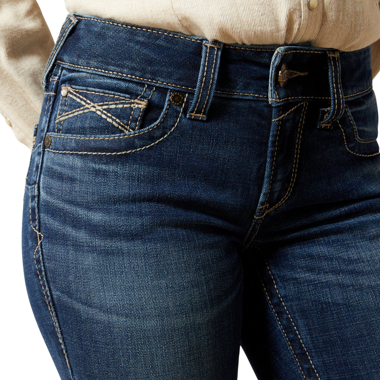 Close-up of blue jeans with a beige shirt underneath on a white background