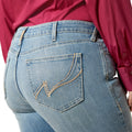 Close-up of blue jeans with a brand logo on the pocket, worn by a person in a red shirt.