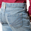 Close-up of blue jeans with a visible Ariat brand label on a white background