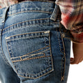 Close-up of blue jeans with a plaid shirt partially visible