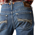 Close-up of blue jeans with Ariat branding on a white background