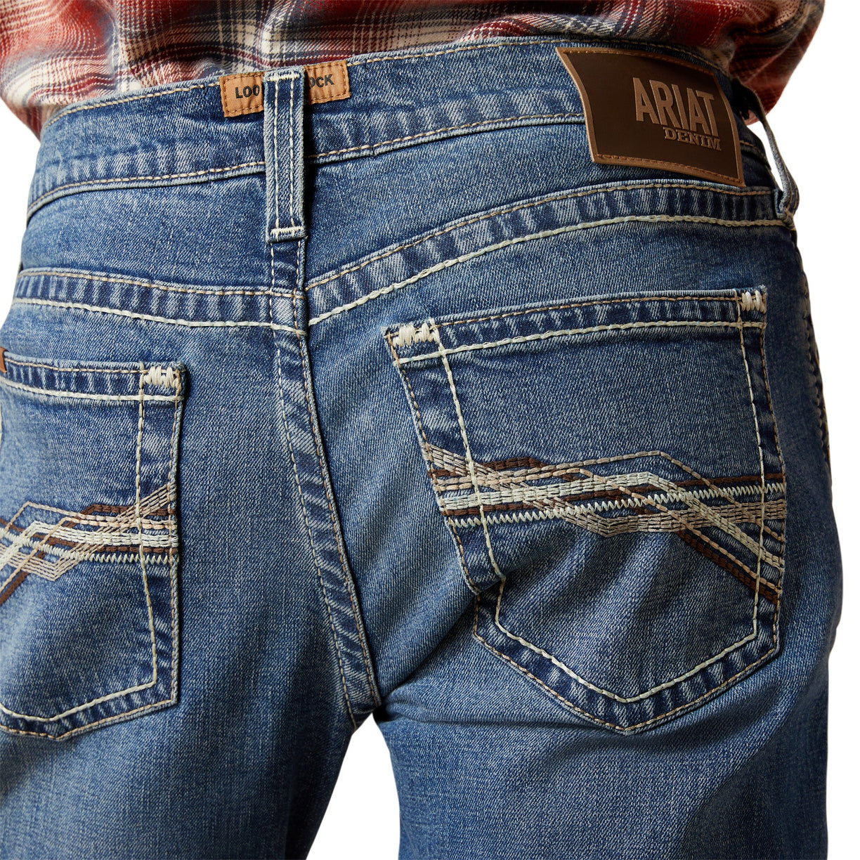 Close-up of blue jeans with Ariat branding on a white background