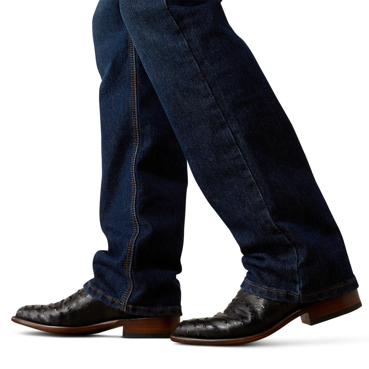 Dark blue jeans worn with brown leather boots on a white background