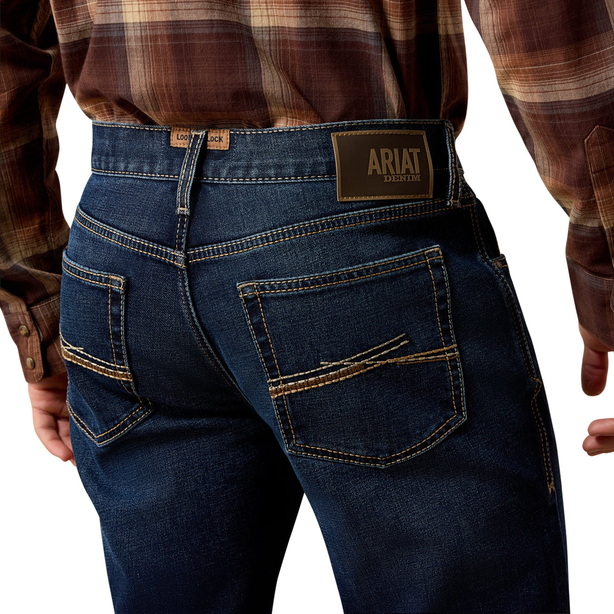 Person wearing blue jeans with Ariat logo on a white background