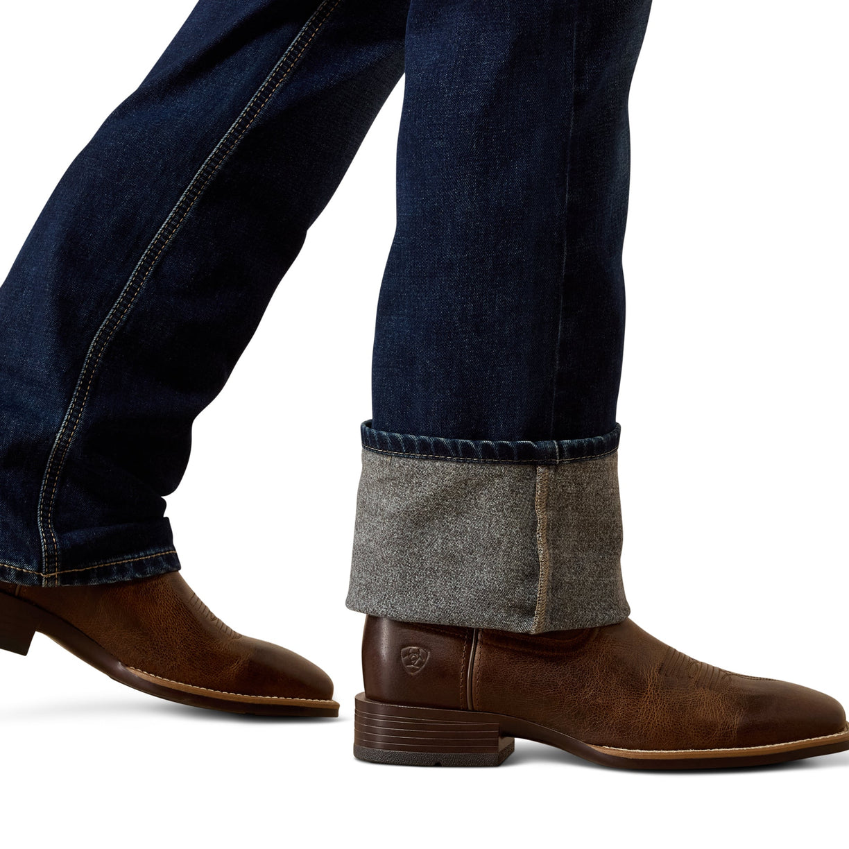 Brown leather boots with rolled-up jeans on a white background