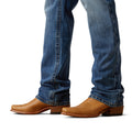 Brown leather boots worn with blue jeans on a white background
