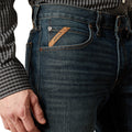 Close-up of a person wearing blue jeans with a brand label, on a white background.
