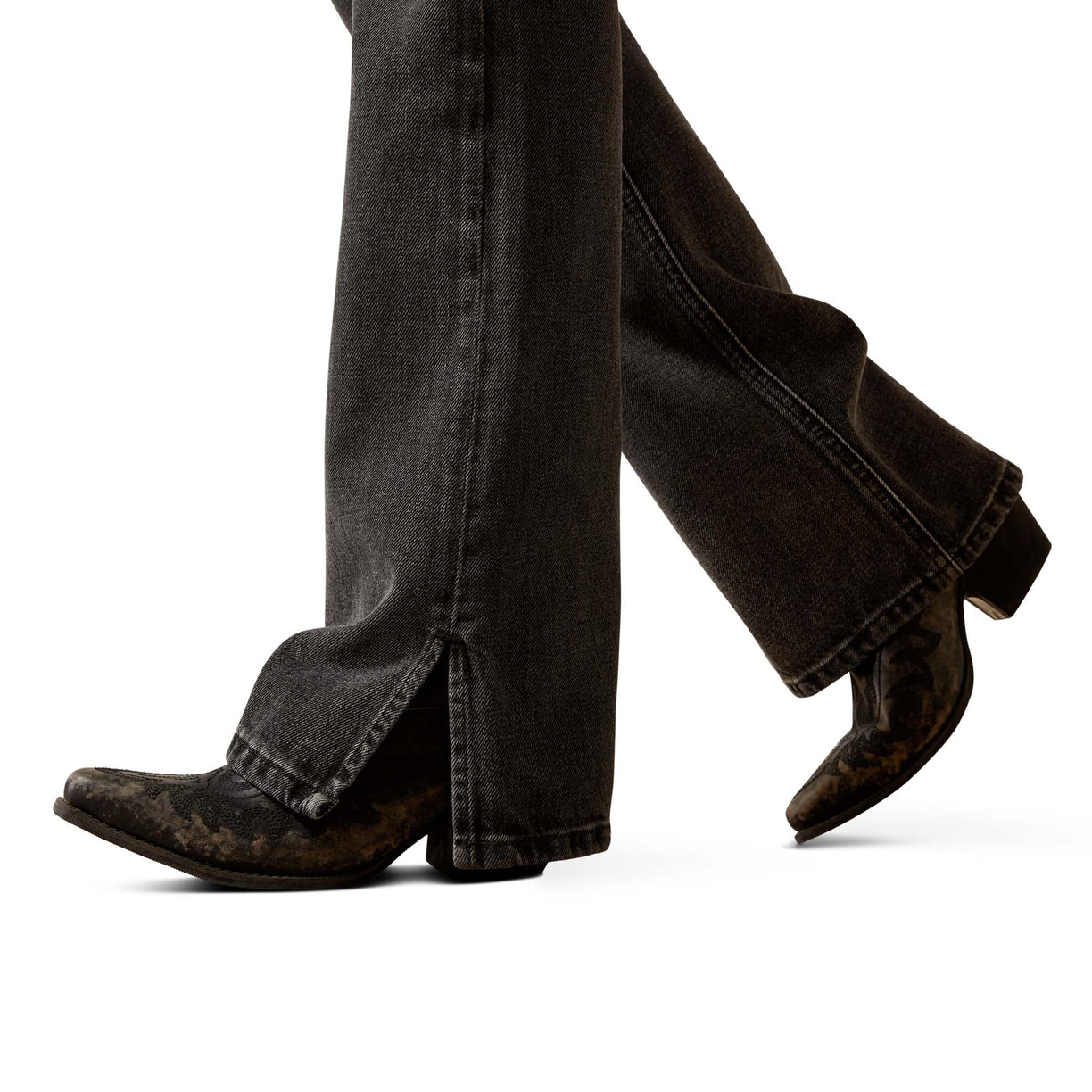 Person wearing black jeans and brown boots on a white background