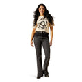 Woman wearing a beige t-shirt with graphic design and dark jeans on a white background