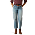 Person wearing light blue jeans and brown shoes on a white background