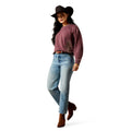 Woman wearing a pink sweater, blue jeans, and a cowboy hat on a white background