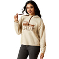 Woman wearing a cream hoodie with 'Ariat' logo on a white background