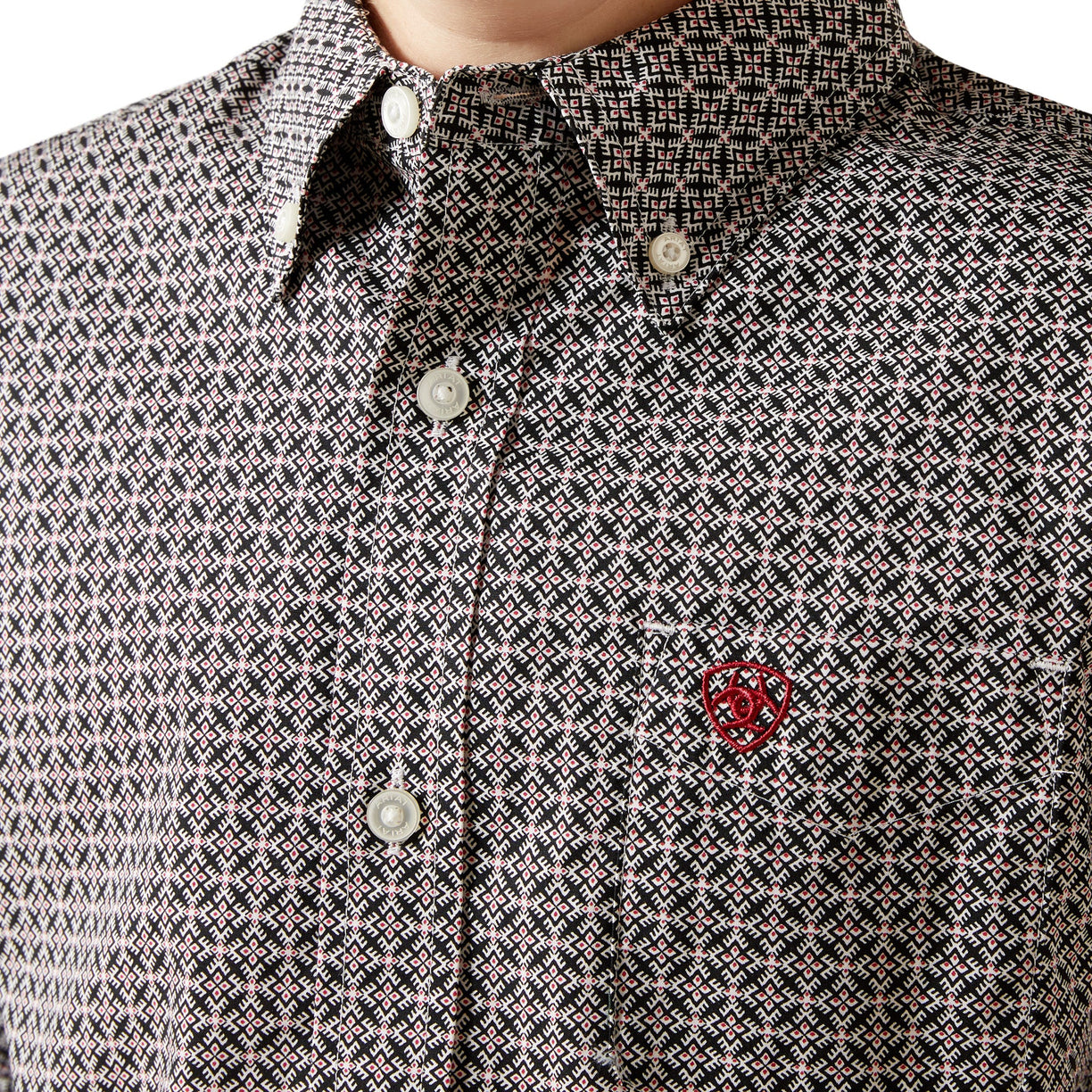 Close-up of a patterned shirt with a red logo on the chest.