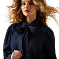 Woman wearing a dark blue coat with a bow detail on a white background