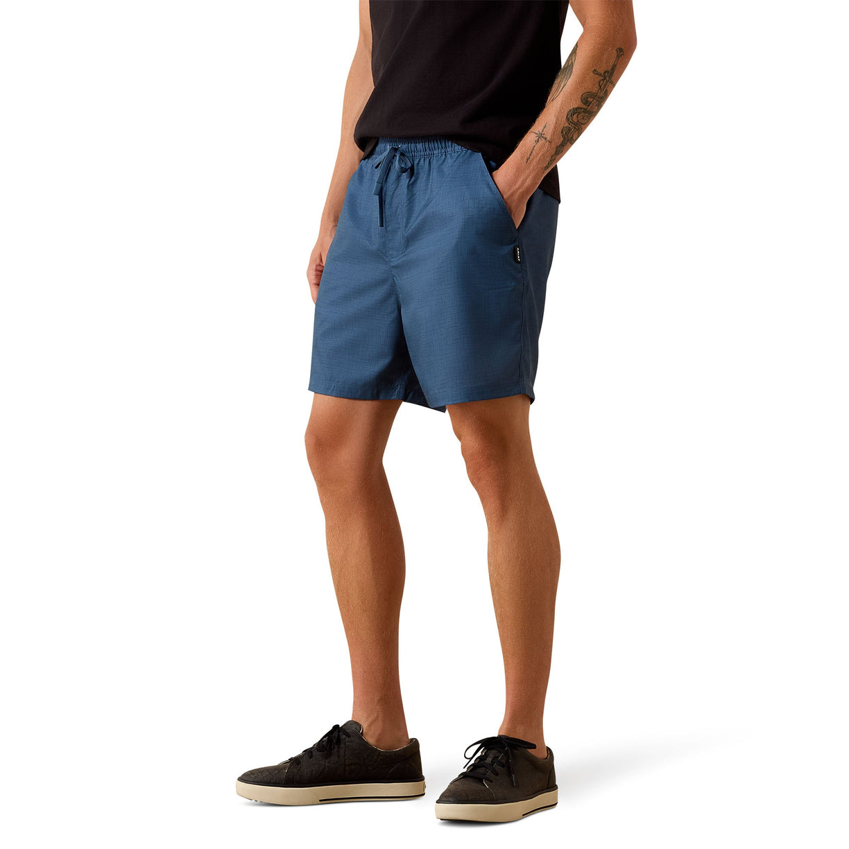 A person wearing blue drawstring shorts, a black t-shirt, and black sneakers, shown from the waist down against a plain white background.