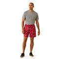 Man wearing a gray t-shirt and red patterned shorts on a white background