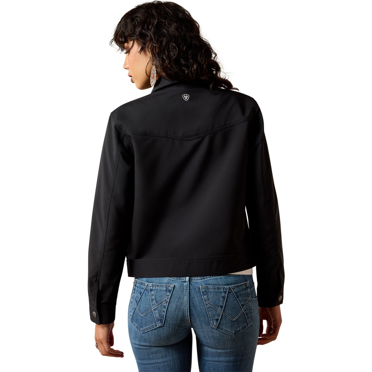 A woman shown from the back wearing a black cropped jacket and blue jeans against a plain white background.