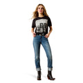 A woman modeling a black short-sleeve graphic T-shirt with a large black-and-white print on the front, paired with blue jeans and dark brown ankle boots, against a plain white background.