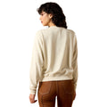 Woman wearing a beige sweater and brown pants on a white background