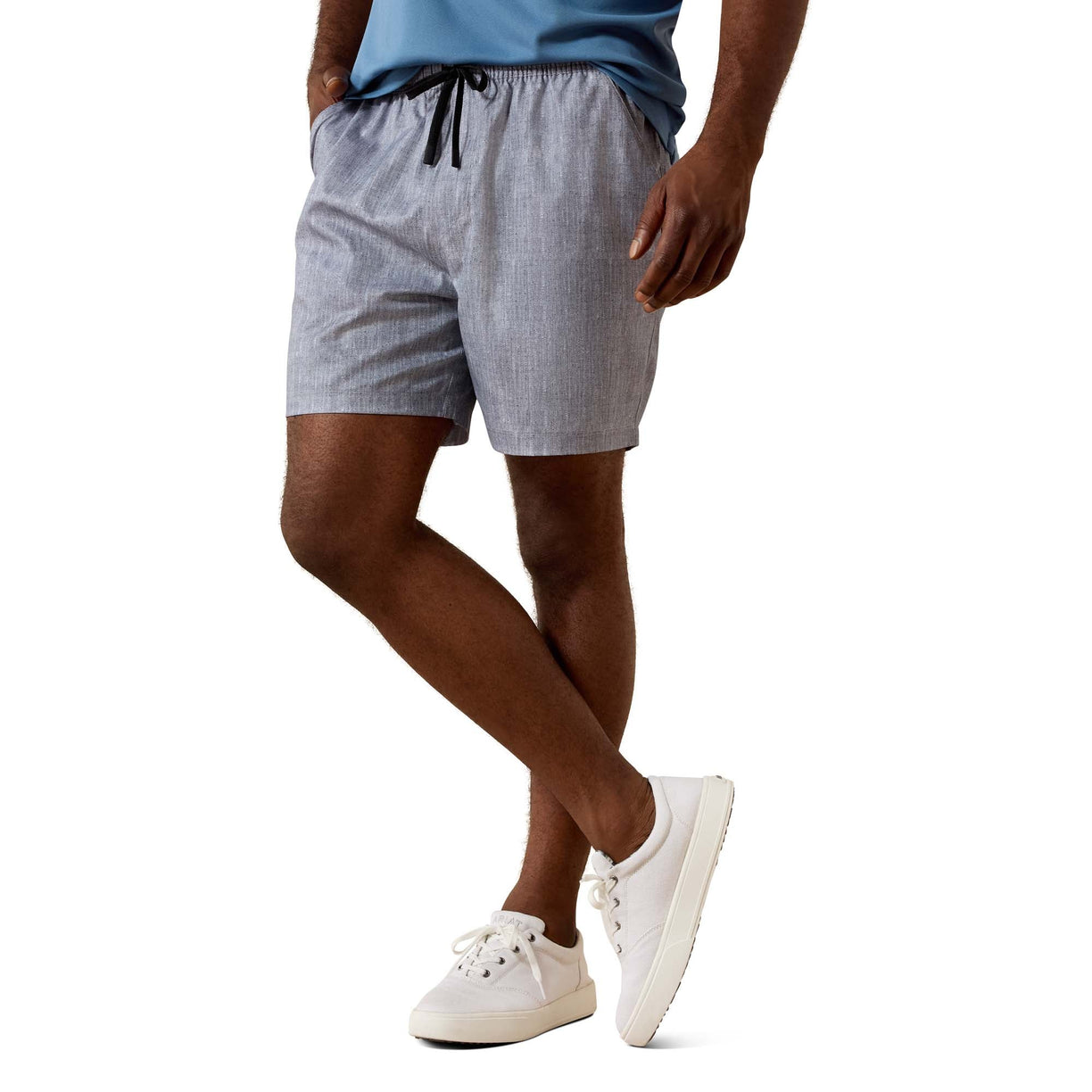 A person wearing light gray textured drawstring shorts, a blue t-shirt, and white sneakers, shown from the waist down against a plain white background.
