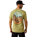 Man wearing a green t-shirt with a desert landscape graphic and 'Ariat' branding.